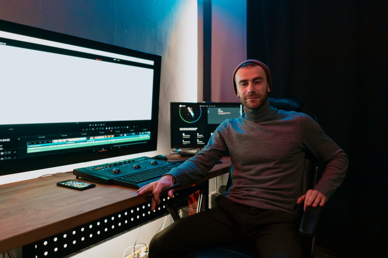 male video editor working on his personal computer with big blank display
